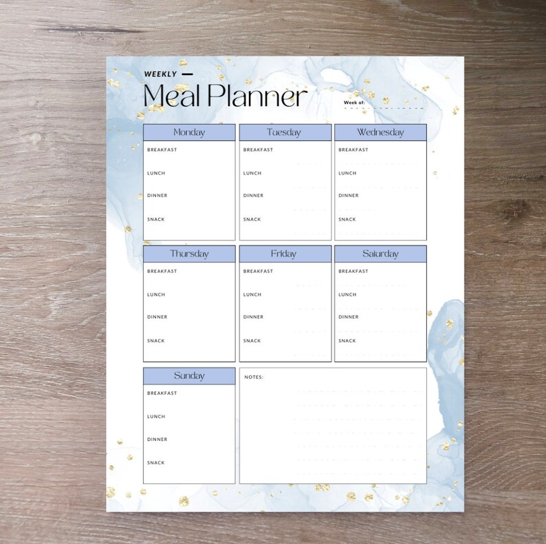 May include: A weekly meal planner with a blue and white watercolor background and gold glitter accents. The planner is divided into seven sections for each day of the week, with spaces for breakfast, lunch, dinner, and snack.