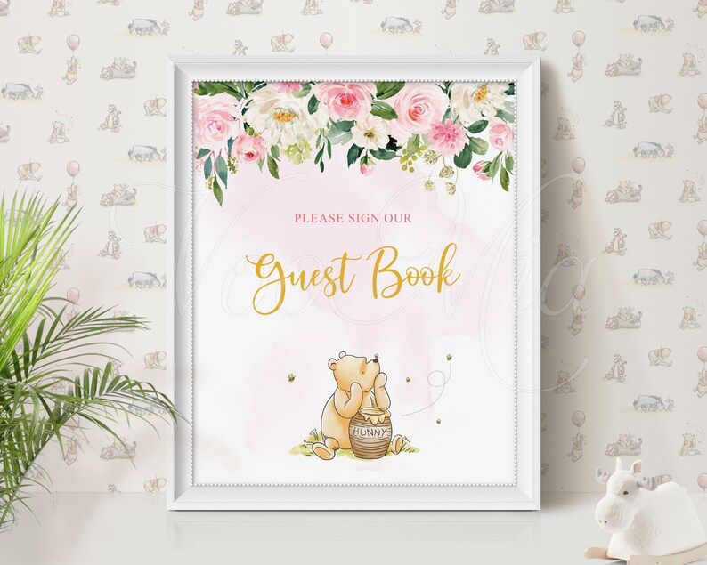 Puede incluir: Un cartel de libro de visitas floral rosa y blanco con una ilustraci&oacute;n de Winnie the Pooh. El cartel dice "Por favor, firme nuestro libro de visitas" en letras doradas. Winnie the Pooh est&aacute; sosteniendo un tarro de miel y hay abejas volando a su alrededor.