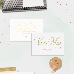 K&ouml;nnte beinhalten: Eine wei&szlig;e Karte mit goldener Schrift, auf der "Voo Mia" und "Vielen Dank!" steht. Die Karte liegt auf einem wei&szlig;en Hintergrund mit goldenen Sternen.