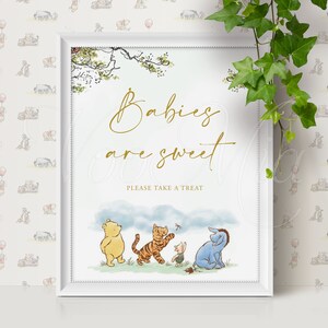 K&ouml;nnte beinhalten: Ein wei&szlig;er gerahmter Druck mit Winnie Puuh-Motiv. Der Druck zeigt Winnie Puuh, Ferkel, Tigger und Esel, die auf einem Feld stehen. Der Text auf dem Druck lautet "Babies are sweet. Please take a treat."