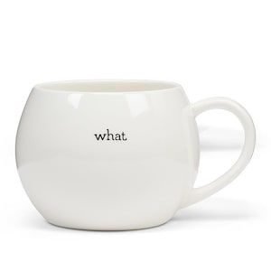 May include: A white ceramic mug with a rounded body and a curved handle. The word "what" is printed in black on the front of the mug. The mug is designed for beverages.