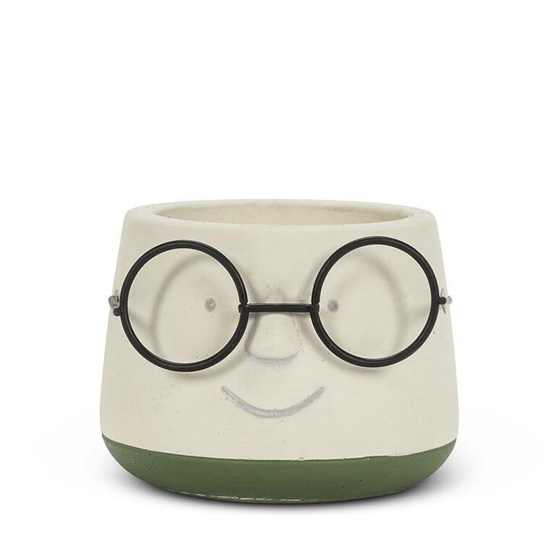 May include: A whimsical, off-white ceramic planter with a smiling face and black wire-rimmed glasses. The base of the planter is a dark green. This decorative pot is ideal for small plants and adds a touch of personality to any space.
