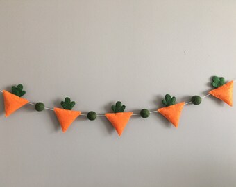 May include: A garland of felt carrots with green tops and green felt balls strung on white twine.