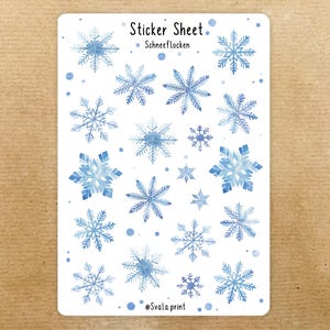 Könnte beinhalten: Ein Stickerbogen mit Aquarell-Schneeflocken in verschiedenen Blautönen. Der Bogen enthält den Text "Sticker Sheet" und "Schneeflocken". Die Aufkleber sind auf weißem Hintergrund angeordnet, ideal für Winterdekorationen.