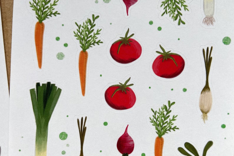 May include: A collection of colorful vegetable stickers, including red tomatoes, orange carrots, green leeks, and white onions. The stickers are on a white background with green dots.