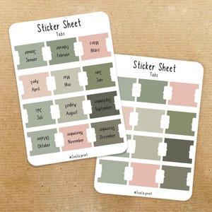 Könnte beinhalten: Zwei Stickerbögen mit monatlichen Registerkarten in gedämpften Grün-, Rosa- und Grautönen. Jede Registerkarte ist mit einem Monat beschriftet. Der Text "Sticker Sheet Tabs" steht oben auf jedem Bogen. Der Hintergrund ist hellbraun.