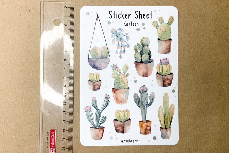 Może przedstawiać: Arkusz naklejek z akwarelowymi ilustracjami r&oacute;żnych kaktus&oacute;w w doniczkach. Arkusz zawiera tekst "Sticker Sheet Kakteen" i podpis artysty. Obok arkusza naklejek umieszczono linijkę.