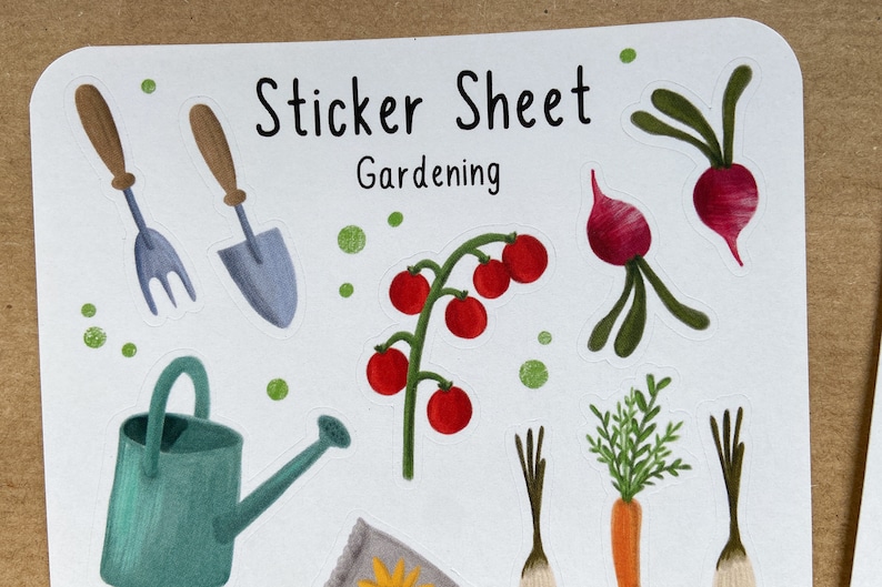 May include: Sticker sheet with a gardening theme. The sheet includes a watering can, a trowel, a fork, a tomato plant, two radishes, two carrots, and a seed packet. The sheet is white with green and brown dots.