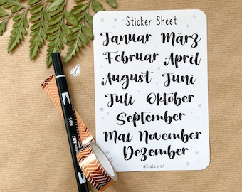May include: A white rectangular sticker sheet with rounded corners featuring the text Sticker Sheet at the top and the months of the year in German written in black calligraphy. The sheet includes small silver dots and the text Svala.print at the bottom.
