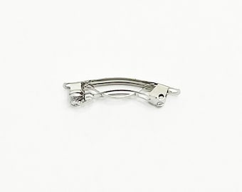 May include: A silver metal hair clip with a curved shape.