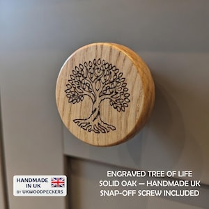 Puede incluir: Pomo de armario redondo de madera con un diseño grabado de árbol de la vida. El pomo es de roble macizo y tiene un acabado de veta de madera natural. El texto "HANDMADE IN UK" es visible. Incluye tornillo desmontable.