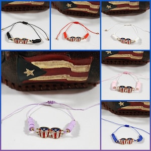 Könnte beinhalten: Ein Set bunter Freundschaftsarmbänder mit einem Design der puerto-ricanischen Flagge mit zwei Trommeln. Die Armbänder sind aus verstellbarer Schnur gefertigt und in Schwarz, Rot, Weiß, Rosa, Lila und Blau erhältlich.