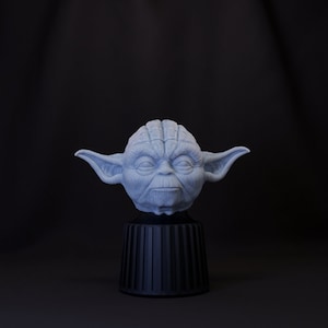 May include: A light blue Yoda figurine with a black base. The figurine is a detailed replica of the character from Star Wars.