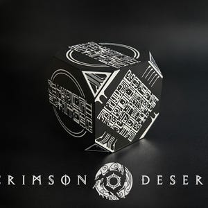 May include: A black cube featuring white geometric patterns and intricate symbols on its faces. The text CRIMSON DESERT is printed in white below the cube, accompanied by a circular emblem depicting stylized creatures in a ring formation.