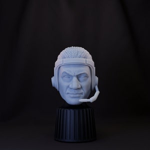 Puede incluir: Un busto blanco impreso en 3D de una persona con auriculares. El busto está sobre una base cilíndrica negra.