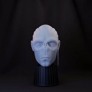 Puede incluir: Un busto de un extraterrestre impreso en 3D en blanco con una oreja larga y fina. El busto está sobre un pedestal negro.