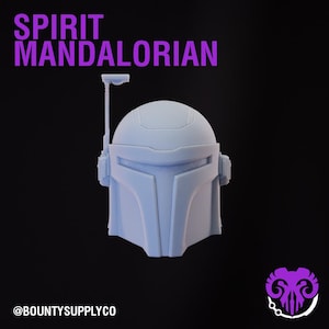 May include: A light blue Mandalorian helmet with a distinctive T-shaped visor and antenna. The words "SPIRIT MANDALORIAN" are in purple text above the helmet. The Etsy shop's logo and handle are at the bottom.