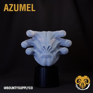 May include: A light blue alien head sculpture with the word "AZUMEL" in gold letters at the top. The sculpture has multiple finger-like appendages and is mounted on a black base. The @BOUNTYSUPPLYCO logo is at the bottom.