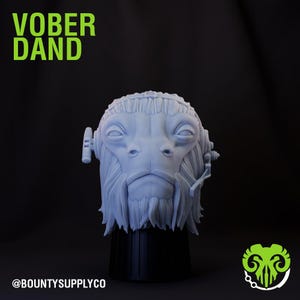 May include: A 3D printed gray bust of a fictional character with a beard and a headset. The bust is on a black base. The text "VOBBER DAND" is in green letters at the top of the image. The text "@BOUNTYSUPPLYCO" is at the bottom of the image.