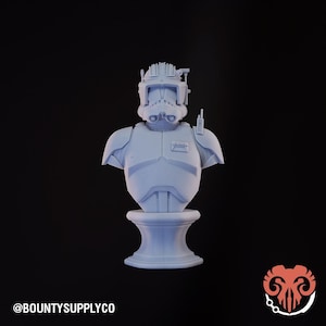 Puede incluir: Busto azul claro de un personaje con casco y armadura, sobre un fondo negro. El busto está montado sobre un pedestal. El texto "@BOUNTYSUPPLYCO" está en la parte inferior izquierda.