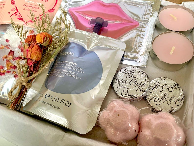 May include: A gift box filled with beauty products. Includes a bouquet of dried flowers, shampoo sachet, lip mask, two pink candles, two wrapped Elizabeth Shaw chocolates, and two pink flower-shaped bath bombs.
