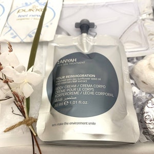 May include: A gift set featuring a white pouch of body cream, a small bouquet of dried flowers, and other spa products. The body cream is labeled "ANYAH ECO SPA TREATMENT" and "YOUR REINVIGORATION". The set includes a 50 ml pouch of body cream.