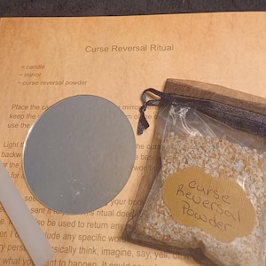 May include: A white candle, a small round mirror, and a small brown bag with a label that reads "Curse Reversal Powder" on a beige background. The text "Curse Reversal Ritual" is at the top of the page. The instructions for the ritual are written below the title.