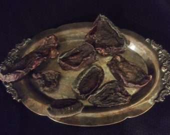 May include: A silver serving tray with eight pieces of dried fruit on it. The fruit is dark brown and has a wrinkled texture.