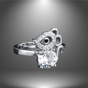 Könnte beinhalten: Ein silberner Ring mit einem Mausdesign. Die Maus hat einen großen, klaren Edelstein für den Körper und kleinere, klare Edelsteine für die Augen. Die Ohren der Maus sind aus Silber und haben einen schwarzen Edelstein in der Mitte.