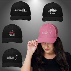 Peut inclure: Cinq casquettes de camionneur différentes avec des motifs sur le thème du rat. Les casquettes sont noires, roses et grises. Les motifs comprennent "Only Rats", "Rats", "My Rat Thinks You're Gross Too" et "Rat Lady" avec une illustration de rat.