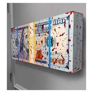 May include: An artwork showing a stack of $100 bills, with red paint splatters. The bills are secured with blue and yellow bands. The artwork is mounted on a grey wall.