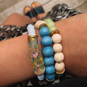 Puede incluir: Un conjunto de tres pulseras con cuentas de colores. La pulsera superior es blanca con una cuenta tubular transparente con motas de colores. La pulsera del medio est&aacute; hecha de cuentas de color azul claro y crema. La pulsera inferior est&aacute; hecha de cuentas de color verde claro y crema.