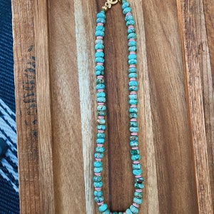 May include: A turquoise and pink beaded necklace with a gold clasp.