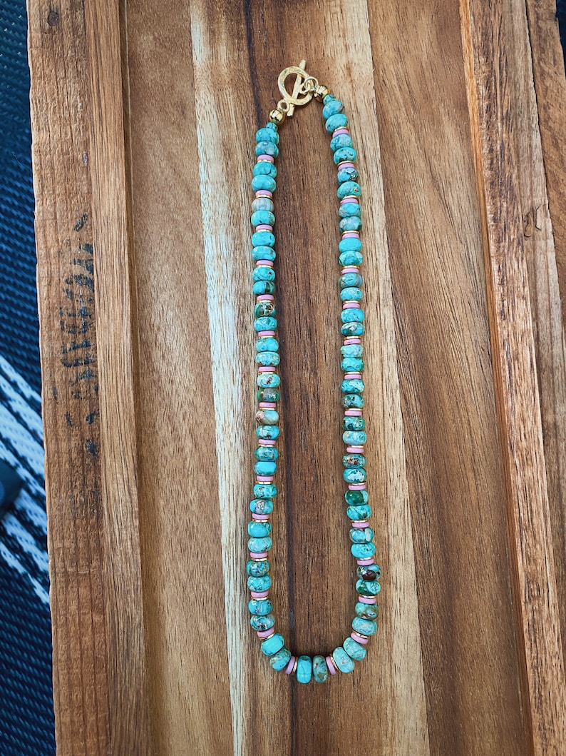 May include: A turquoise and pink beaded necklace with a gold clasp.