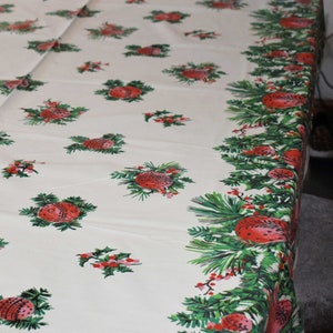 Könnte beinhalten: Weiße Tischdecke mit einem sich wiederholenden Muster aus roten und grünen Stechpalmenzweigen und Ornamenten.
