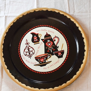 May include: A black metal tray with a gold rim and a white, red, and black design of a coffee pot, cups, and a sugar bowl. The text on the tray reads "Let's have coffee, black or with milk, one or two lumps?"