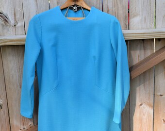 May include: A light blue dress with long sleeves and a round neckline. The dress is made of a textured fabric and has a fitted silhouette.