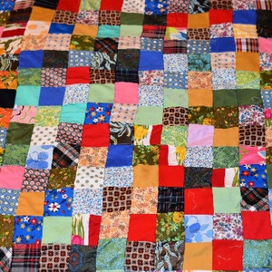 K&ouml;nnte beinhalten: Eine Patchwork-Decke mit einer Vielzahl von Farben und Mustern, darunter Rot, Blau, Gr&uuml;n und Gelb. Die Decke besteht aus Quadraten aus verschiedenen Stoffen, die jeweils ein einzigartiges Design aufweisen.