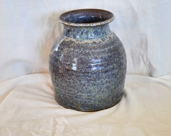 May include: A handmade ceramic vase with a speckled glaze in shades of brown, blue, and white.