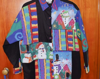 May include: A black button-up shirt with a colourful patchwork design featuring snowmen and winter scenes. The shirt has a collar and long sleeves. The text "SKYSCRAPER" is visible on the label.