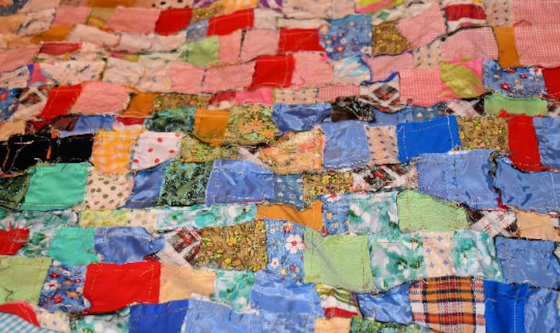 K&ouml;nnte beinhalten: Eine Patchwork-Decke aus verschiedenen Stoffen in unterschiedlichen Farben und Mustern. Die Decke besteht aus Quadraten und Rechtecken aus Stoff, die zusammengen&auml;ht sind.