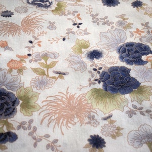 May include: A white fabric with a floral pattern featuring blue, pink, and green flowers. The fabric has a subtle texture and a vintage aesthetic.