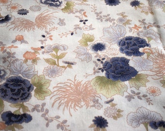 Könnte beinhalten: Ein weißer Stoff mit einem floralen Muster mit blauen, rosa und grünen Blumen. Der Stoff hat eine subtile Textur und eine Vintage-Ästhetik.