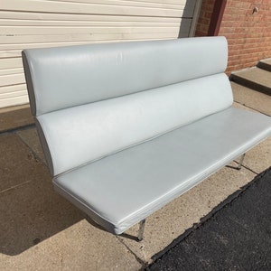 May include: A light gray, three-cushioned sofa with a chrome frame.