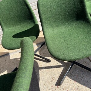 May include: Four green fabric swivel chairs with black metal bases. The chairs are arranged in a semi-circle.