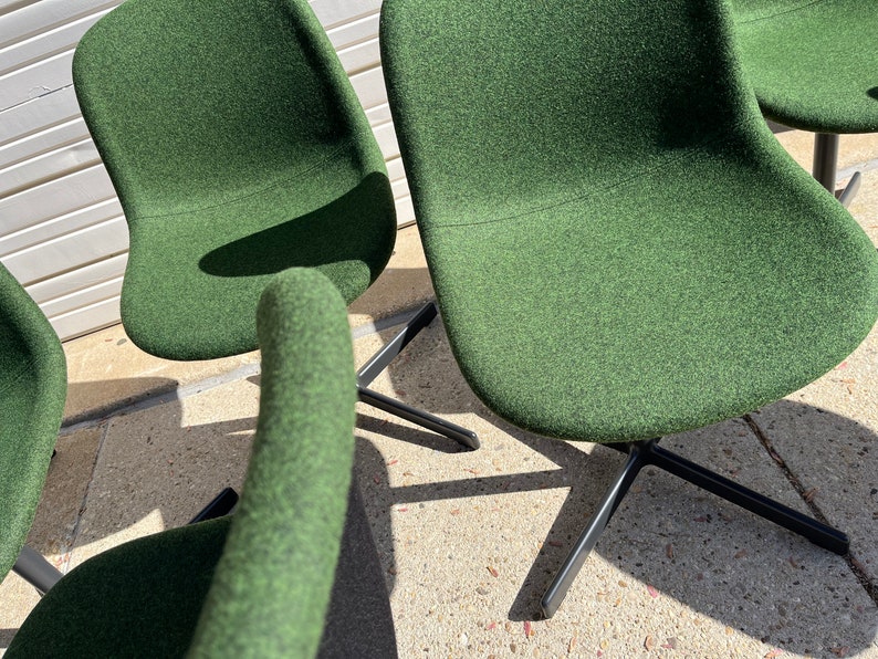 May include: Four green fabric swivel chairs with black metal bases. The chairs are arranged in a semi-circle.
