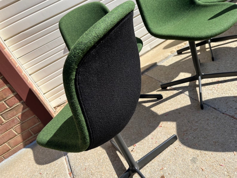 May include: Four green swivel chairs with black metal bases. The chairs have a black fabric back and a green fabric seat.