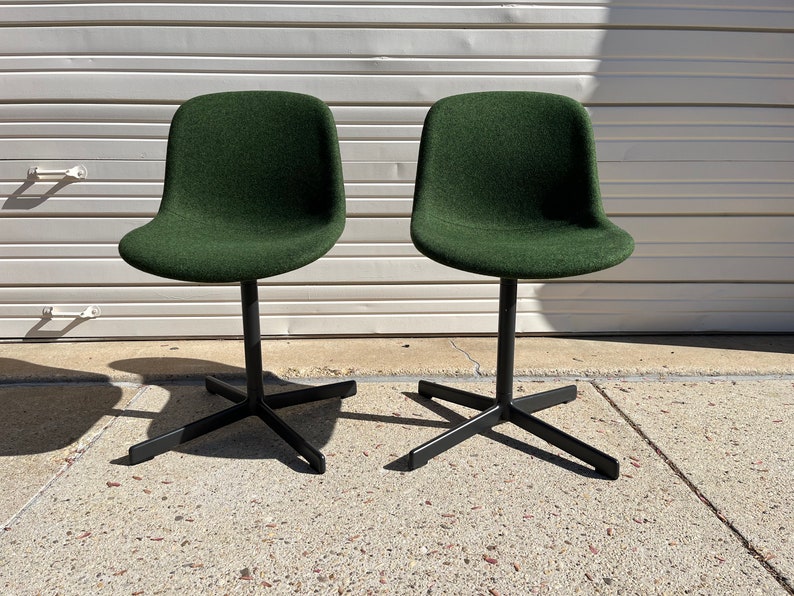 May include: Two dark green swivel chairs with black metal bases. The chairs are on a concrete surface.