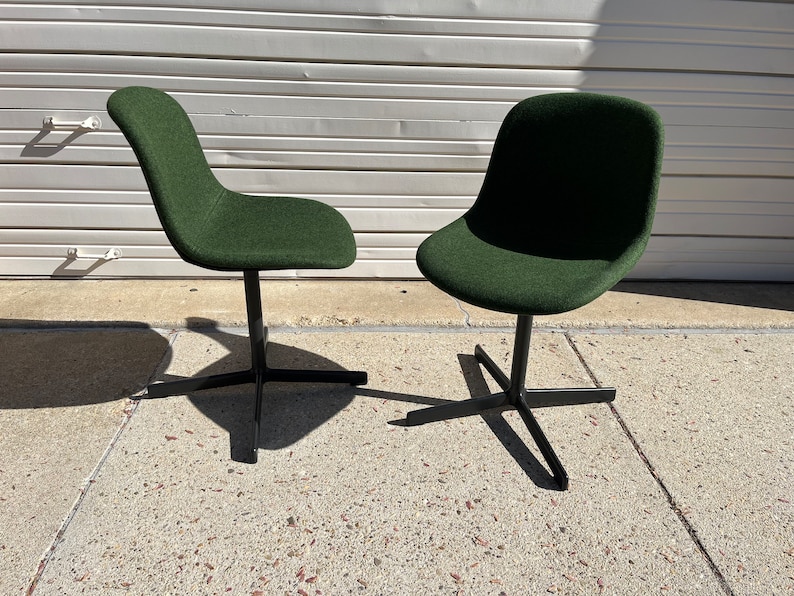 May include: Two dark green swivel chairs with black metal bases. The chairs are on a gray concrete surface.