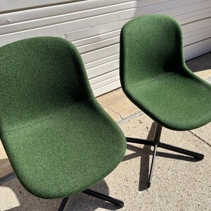 May include: Two dark green swivel chairs with black metal bases. The chairs are upholstered in a textured fabric.